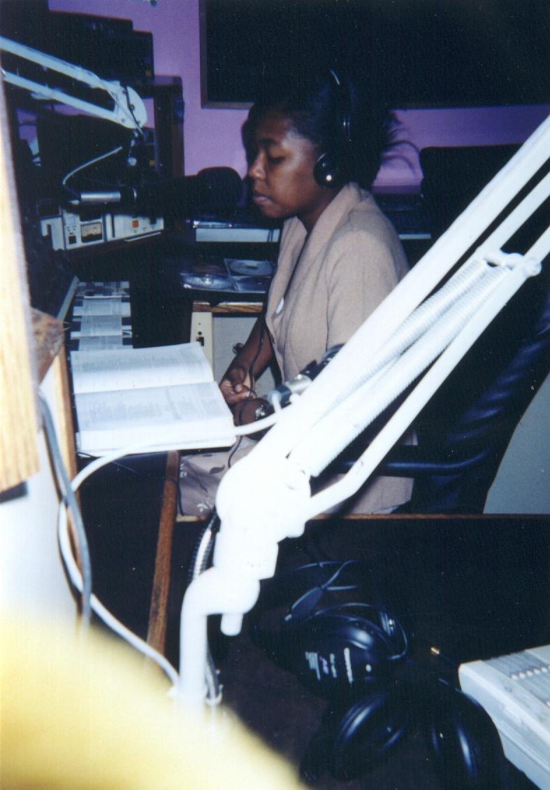 Young Sheila Phicil co-hosting a radio show, headphones on at the mic